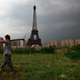 A farmer carrying a rake walks past a replica of the Eiffel Tower in Hangzhou, Zhejiang Province.